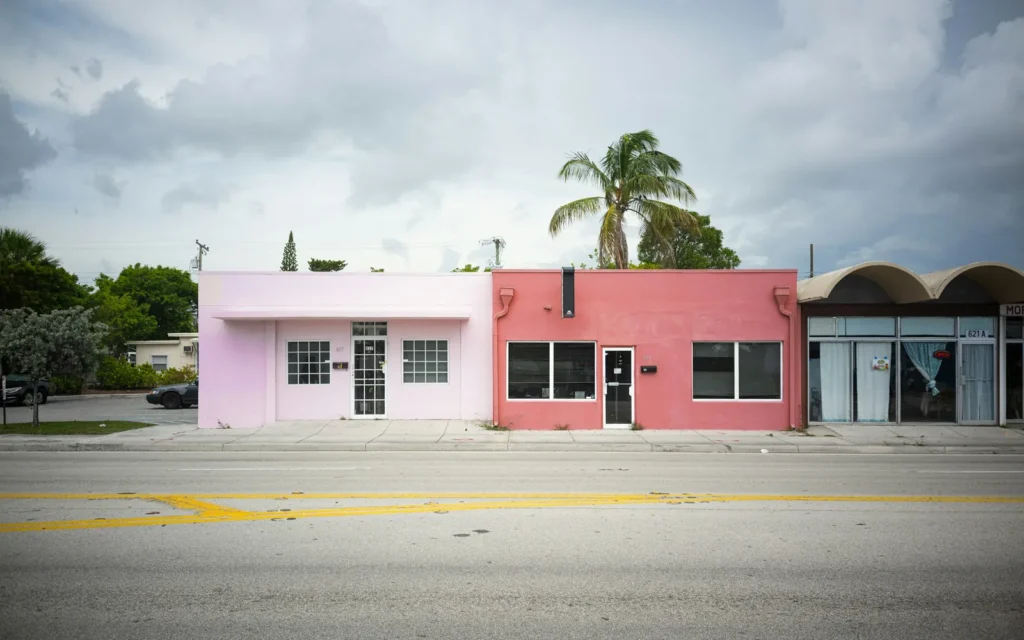 Pastel pink and coral small business storefronts with a palm tree on a South Florida street