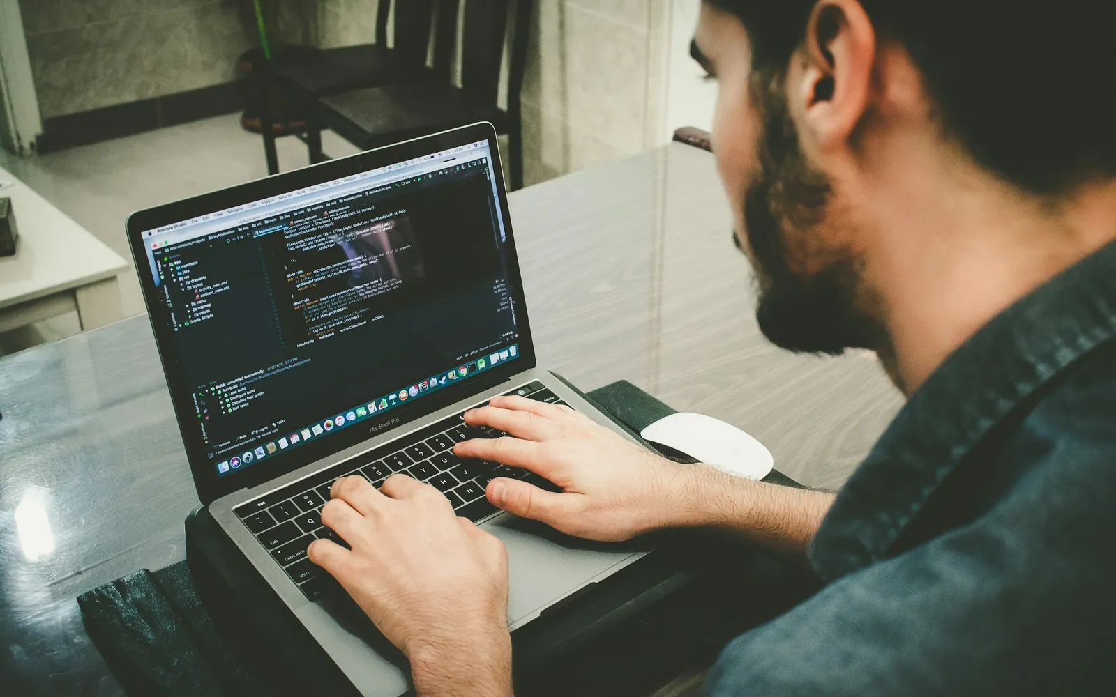 Web developer writing code on a laptop at a wooden desk